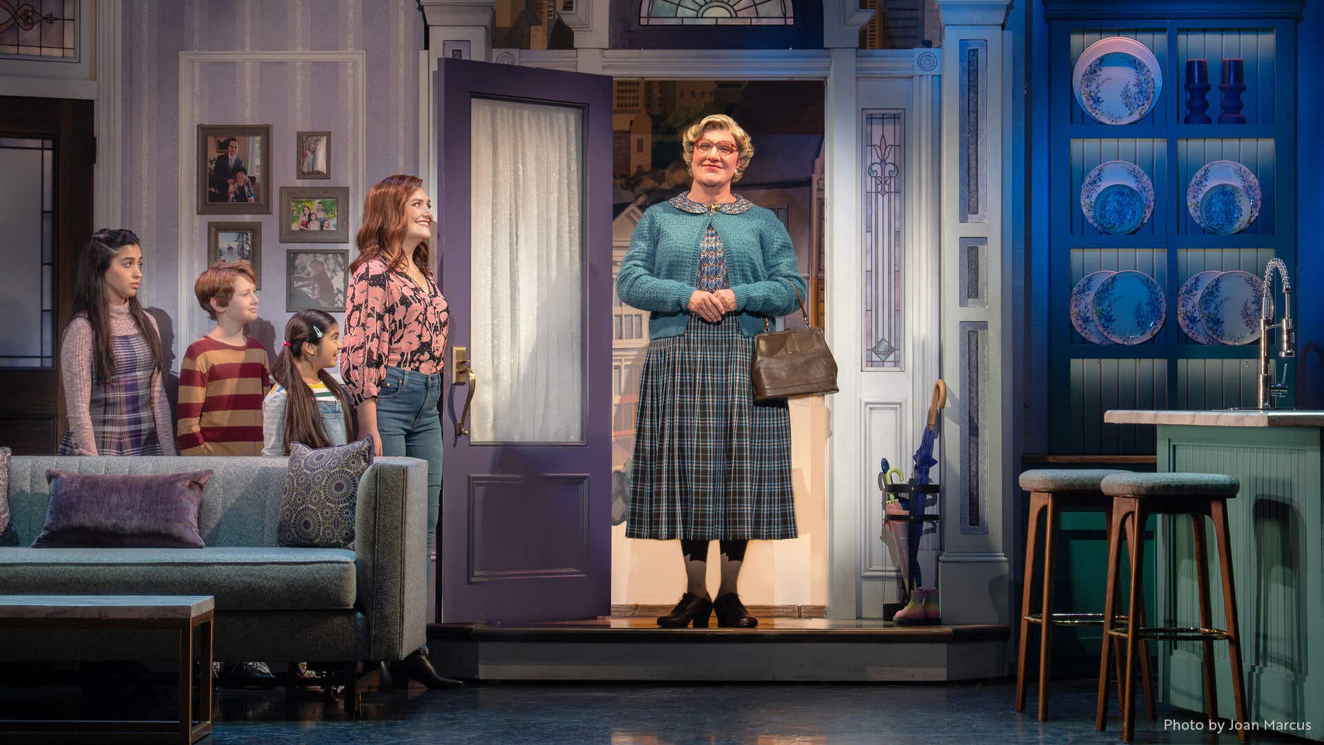 Mrs. Doubtfire standing in the doorway while the family is off to the left. 