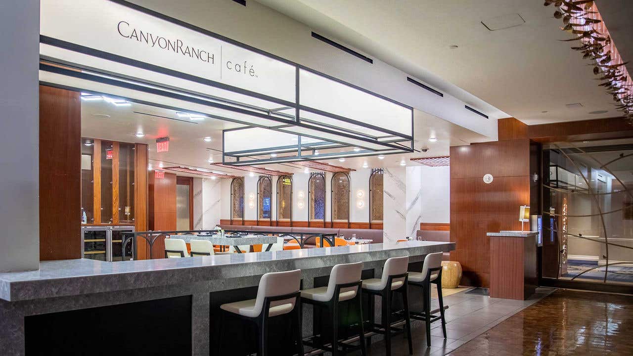 Canyon Ranch Café entrance with a marble counter, bar seating, and a view into a modern dining area.