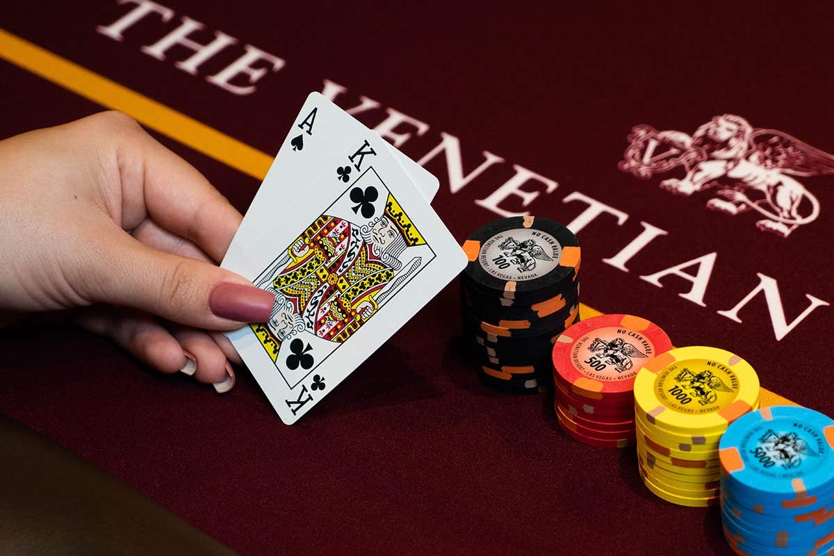 Woman holding two ace cards in front of a stack of poker chips